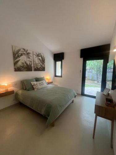 a bedroom with a green bed and a large window at A Villa Rosa in Santa-Maria-di-Lota