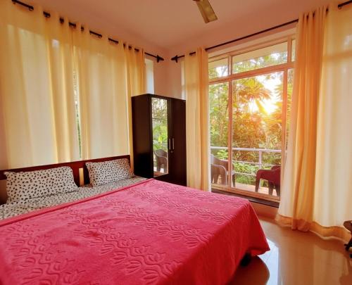 a bedroom with a red bed and a large window at GS Home on the Bay - Sea & forest view glass studio in Vagator