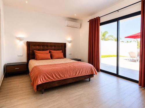 a bedroom with a bed with orange pillows and a balcony at Villa ines in Taguermess