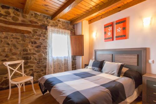 1 dormitorio con cama y pared de piedra en La Casita del Oja, en Ojacastro