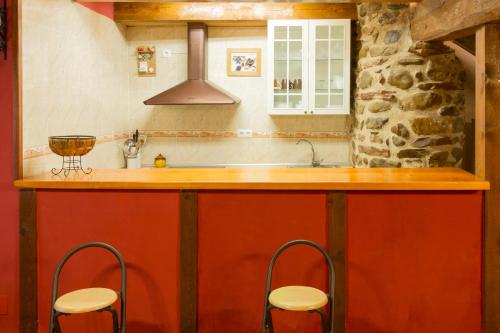 una cocina con encimera con taburetes alrededor en La Casita del Oja, en Ojacastro