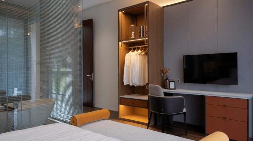 a bedroom with a desk and a bed with a television at Alcola Boutique Villa - Bahama Unit in Malang