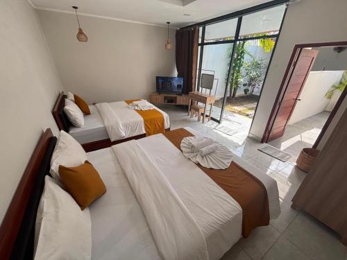a bedroom with three beds and a television in it at Kotoa Villa 68 in Nusa Dua
