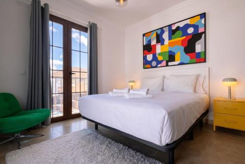 a bedroom with a large white bed and a green chair at Villa La Genuina in Yaiza