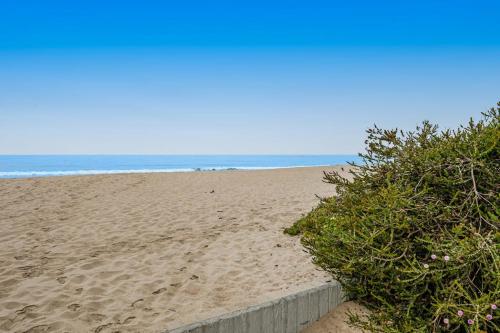 a sandy beach with a retaining wall and the ocean at Sugar Shack in Carpinteria