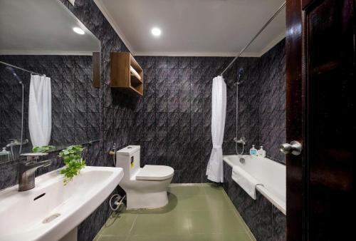 a bathroom with a toilet and a sink and a tub at The Lake Silk Hotel & Travel in Hanoi