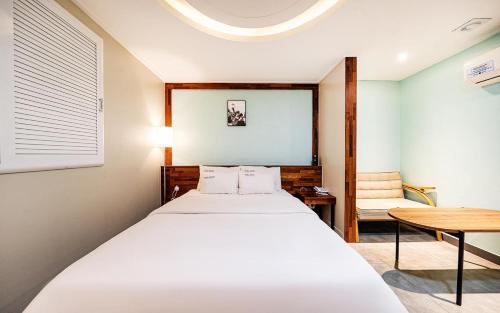 a bedroom with a white bed and a table at Bupyeong Byulha Hotel in Incheon