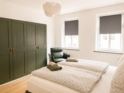 a bedroom with two beds and a chair at Modernes Design-Apartment mit Balkon & WLAN in Bautzen
