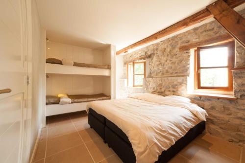 Chateauroux-les-AlpesにあるMaison Cimarronの石壁のベッドルーム(ベッド1台、窓付)