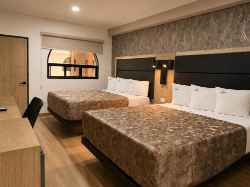 a hotel room with two beds and a desk at Sereno Business Inn in Ensenada