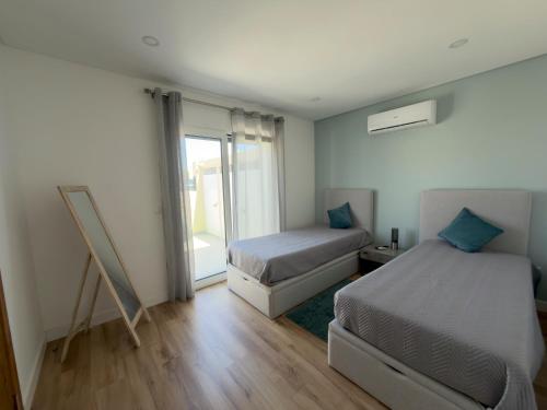 a bedroom with two beds and a window at Vila Grafenola in Montargil