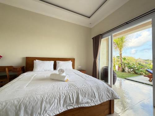 a bedroom with a bed with a teddy bear on it at Bunut Sari Guesthouse in Ungasan