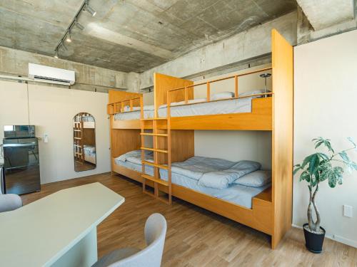 a room with bunk beds and a dining room with a table at By The Tree Room in Amami