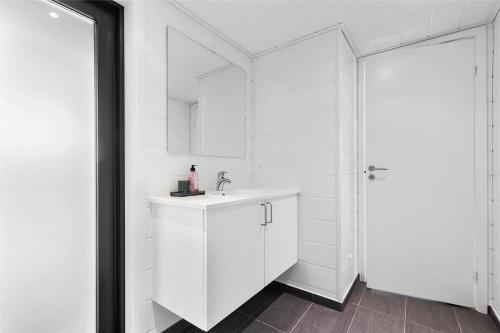 a white bathroom with a sink and a mirror at 10036-Rorvig-Magevej-11 in Rørvig