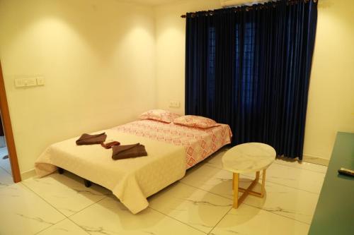 a bedroom with a bed and a table and a chair at The Crownstone Apartment in Trivandrum