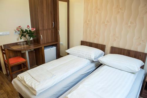 two twin beds in a room with a table and a chair at BL.Apartmanház II. in Szeged