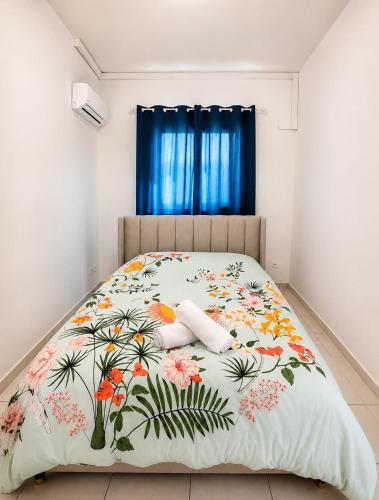 a bedroom with a bed with a floral bedspread at L' Aurore de Cassandre in Saint-Paul