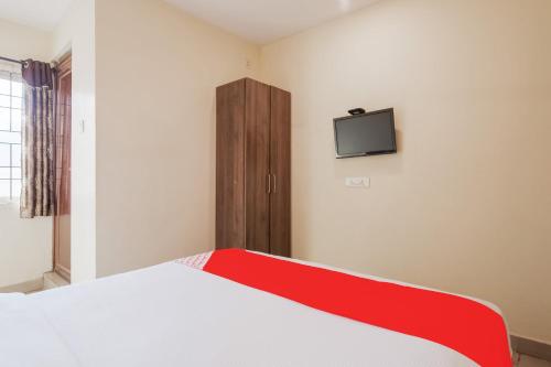 a bedroom with a bed and a tv on the wall at Hotel O Anu Grand in Visakhapatnam