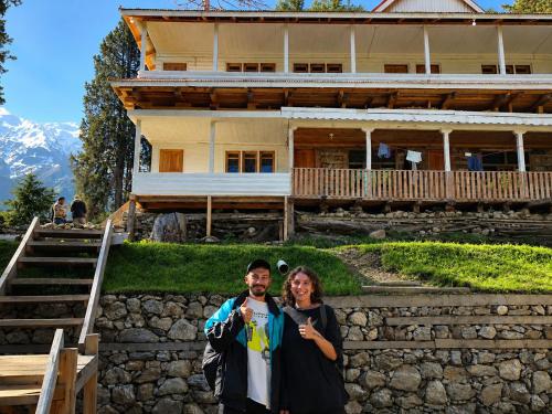 a man and a woman standing in front of a house at Fairy Meadows Comfort Lodges in Tato