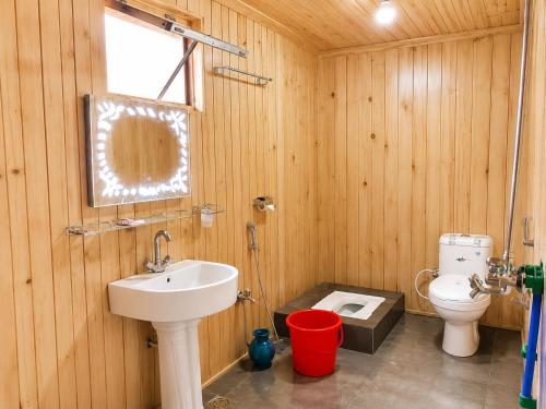 a wooden bathroom with a sink and a toilet at Fairy Meadows Comfort Lodges in Tato