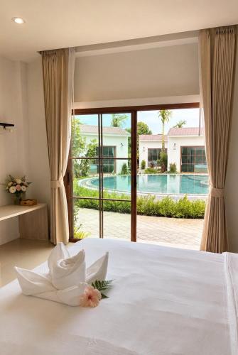 a bedroom with a bed with a view of a pool at Vanda Resort & Villa in Ban Thai Don (1)