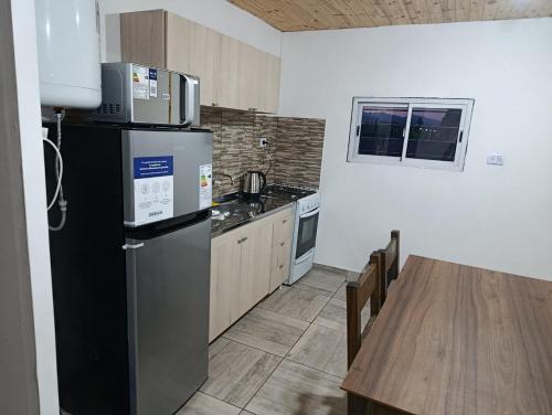 a kitchen with a black refrigerator and a table at Complejo El Mirador in Calingasta
