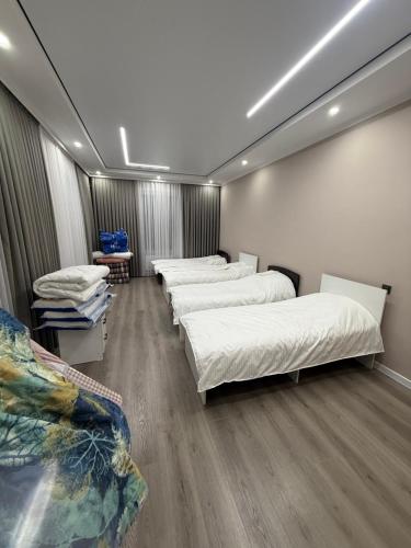 a row of beds in a room with wooden floors at Гостевой дом БАЯН in Cholpon-Ata