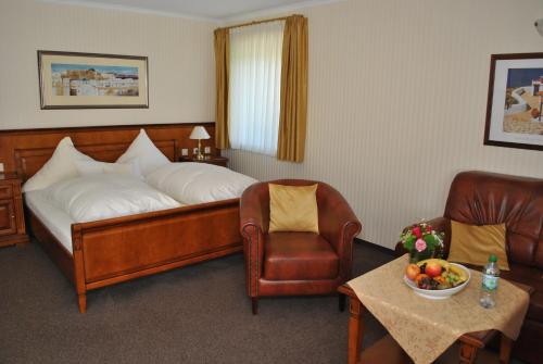 a bedroom with a bed and a chair and a table at Waldhotel Rheinbach in Rheinbach