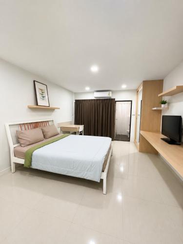a bedroom with a white bed and a television at Peaberry Place - พีเบอร์รี่เพลส in Ban Zong Katiam