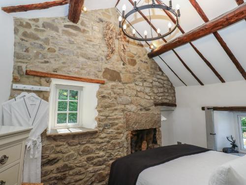 a bedroom with a fireplace in a stone wall at Lydgate Cottage in Eyam