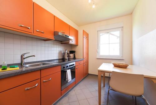 a kitchen with orange cabinets and a sink and a table at Trixi Park Zittauer Gebirge - Ferienhäuser, Hotel und Camping in Großschönau