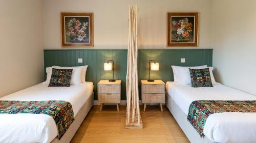 two twin beds in a room with two lamps at Potton Hall in Saxmundham