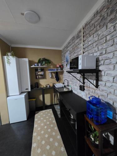 a kitchen with a white refrigerator and a brick wall at The Cottage Inn in Modimolle