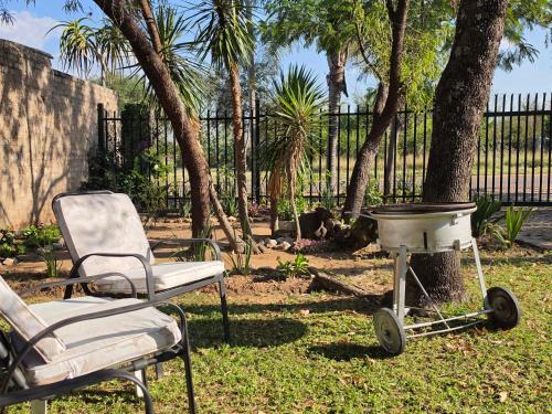 a grill and a chair next to a tree at The Cottage Inn in Modimolle