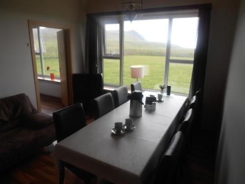 a dining room table with chairs and a large window at Giljur Guesthouse in Vík