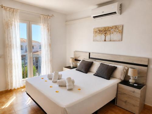 a white bedroom with a large white bed and a window at CASA PUIG, Piscina Privada ,Aire Acondicionado Free in L'Escala