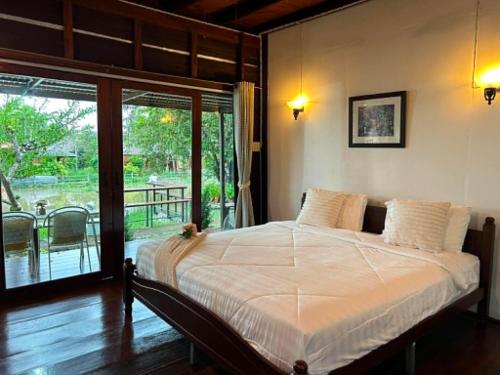 a bedroom with a bed with a view of a patio at Netnatee Amphawa in Ban Plai Khlong Om