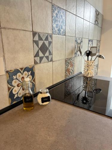 a counter with a bottle of honey and a tiled wall at Siculía in Noto