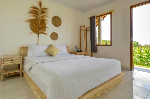 a white bedroom with a large bed and a window at Bee Camp Bedugul by AGATA in Bedugul