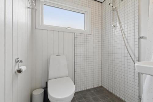 a white bathroom with a toilet and a window at Nordic Style Summer House For Two in Bogense