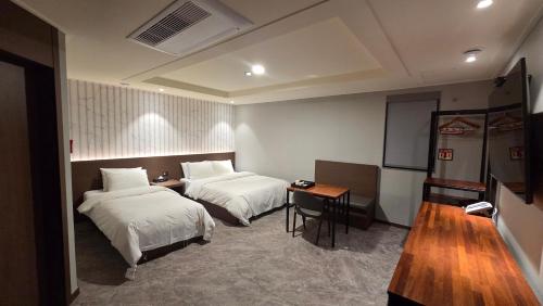 ein Hotelzimmer mit zwei Betten und einem Tisch in der Unterkunft Hotel Cleo in Goyang