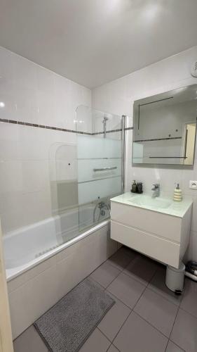 a white bathroom with a sink and a mirror at Cozy Suite La Défense in Nanterre