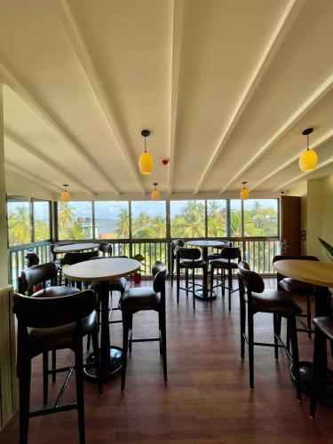 a dining room with tables and chairs and windows at Casa Amarilla Hotel in Dona Paula