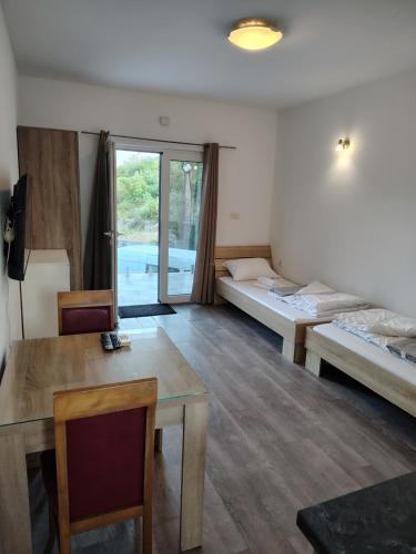 a room with two beds and a table and chairs at B&I apartmani in Glavatske Kućice