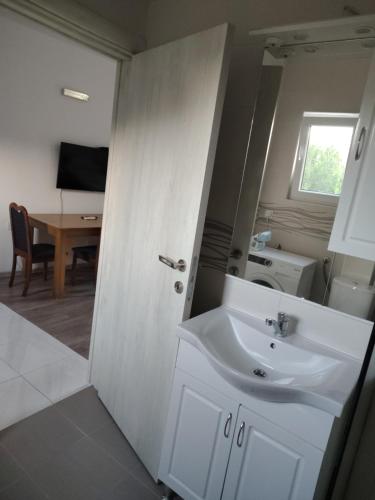 a bathroom with a white sink and a table at B&I apartmani in Glavatske Kućice