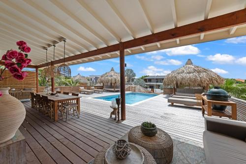 an outdoor deck with a table and chairs and a pool at El Patrón, the villa in Jan Thiel