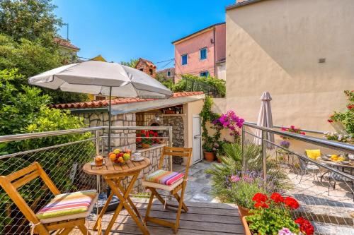 a balcony with a table and chairs and an umbrella at Island Villa Alba with Terrace & Grill - Happy Rentals in Mali Lošinj