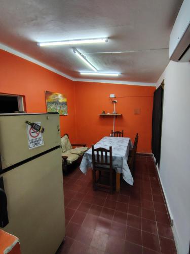 a kitchen with orange walls and a table and a refrigerator at La casita de José in Villa Unión