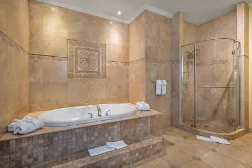 ein großes Badezimmer mit Badewanne und Dusche in der Unterkunft Hotel Brossard, an Ascend Collection Hotel in Brossard