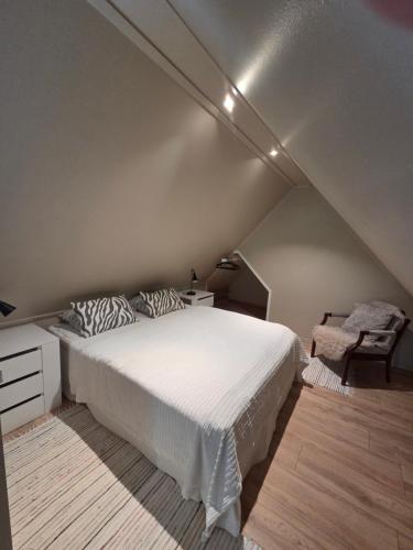 a bedroom with a white bed and a chair at Gammeleken in Stidsvig